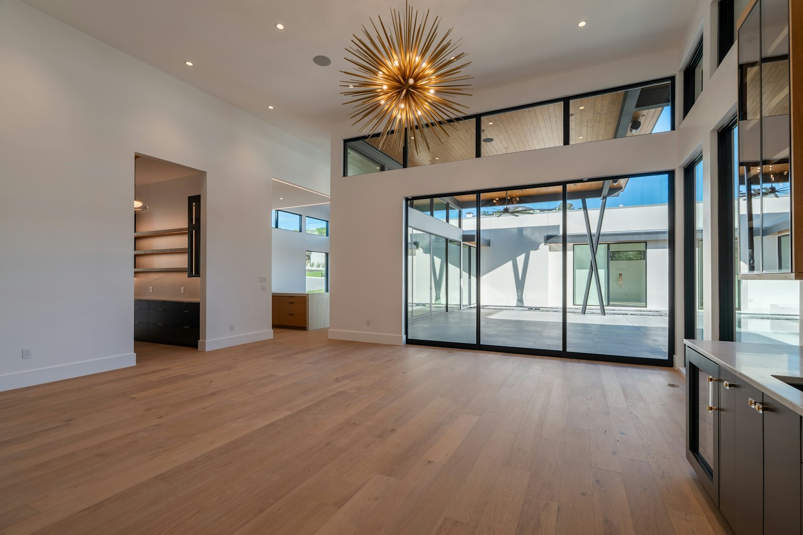 An empty room with wooden floors and tall windows in an unoccupied home